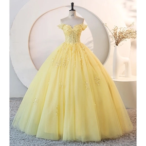 Detailed view of yellow off-shoulder gown with intricate lace appliques and sequins