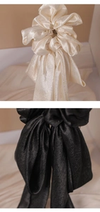 Detail of elegant satin bow scrunchie with long ribbons in champagne and black colors