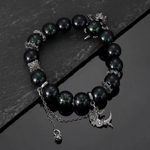 Detail of dark green beaded bracelet featuring silver dragon and crescent moon charms