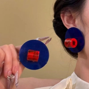 Gros plan sur les boucles d'oreilles rondes en acrylique bleu et rouge au style rétro