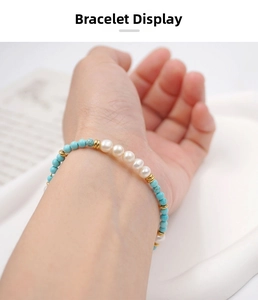 Detail of turquoise and baroque pearl beaded bracelet with gold accents on wrist