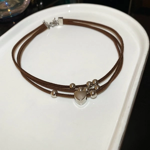 Detail of multi-layer brown leather cord necklace with silver heart pendant and metal beads