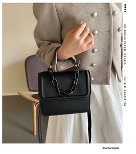 Detail of minimalist black crossbody bag with matte chain strap and leather texture