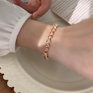 Macro view of rose gold bracelet featuring oval pink zircons on vintage tray
