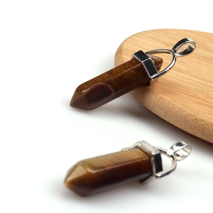 Macro shot of two hexagonal tiger eye stone pendants on a rustic wood slice