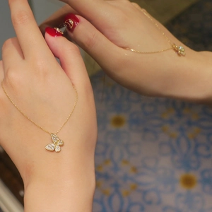 Detail of a gold butterfly necklace with pavé stones shown against a mirror reflection