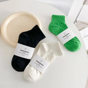 Tre paia di calze minimaliste in cotone in verde, nero e bianco con design essenziale