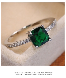 Macro detail of square green zircon ring in a silver four-prong setting on velvet