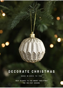 Dettaglio di una pallina di Natale geometrica oro champagne su un albero con luci bokeh