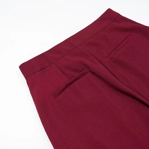 Detailed macro view of the waistband and rear pockets on wine red slim-fit trousers