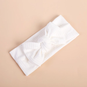 Detailed texture of white knitted ribbed headband with a large minimalist bow design