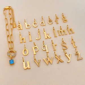 Gedetailleerde close-up van 14K vergulde letterhangers en armband met blauwe steen