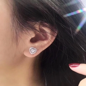 Close-up of heart-shaped silver diamond stud earrings worn on model for a luxury look