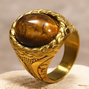 Macro shot of men's gold stainless steel ring with oval tiger eye stone and braided detail