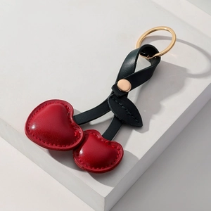 Creative PU leather red cherry keychain with gold metal ring on a white platform