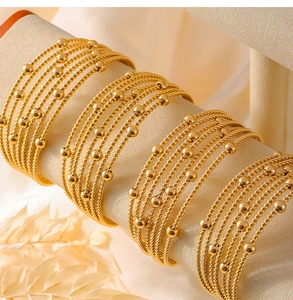 Detail of gold multi-layer spiral bangle with bead accents on a beige velvet stand