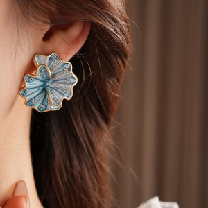 Macro shot of vintage blue enamel flower earring with gold edges and diamond accents