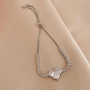 Detailed macro shot of an adjustable heart zircon bracelet on soft champagne satin fabric