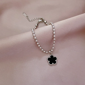 Minimalist silver beaded chain bracelet with black clover pendant on pink satin