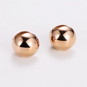 Macro shot of two rose gold polished hollow metal round beads for jewelry making