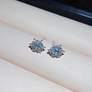 Macro shot of silver snowflake earrings with light blue zircon and halo stones