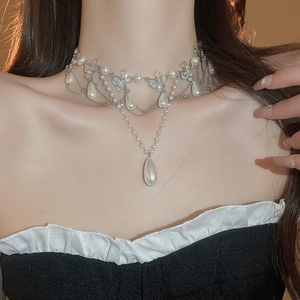 Detail of a silver floral necklace with crystal bows and waterdrop pearls on a model