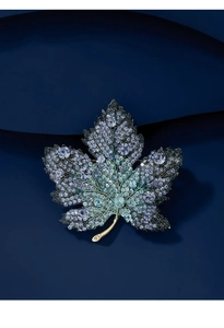 Detailed view of luxury crystal maple leaf brooch with blue rhinestones on textured fabric