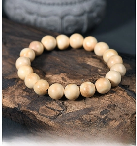 Detailed view of milky white wooden prayer beads on a natural rustic wood background
