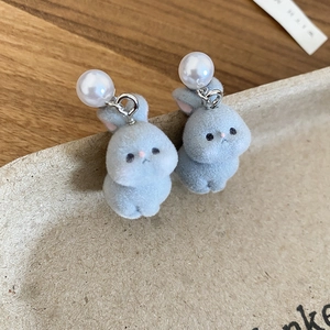 Macro shot of silver needle stud earrings featuring grey flocked bunnies and white pearls