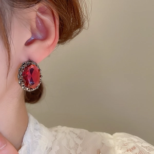 Close-up of a vintage oval red zircon earring worn by a model in a French retro style