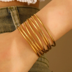 Close-up of stacked gold bangles with textured patterns and polished finish on wrist