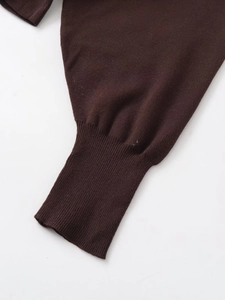 Detail eines dunkelbraunen Strickoberteils mit hochdichtem Stoff und Rippbündchen