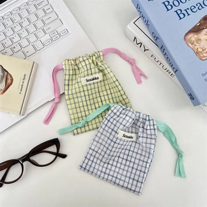 Close-up of checkered drawstring storage bags on a desk with laptop and books