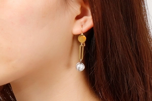 Close-up of minimalist geometric pearl drop earrings worn on ear in golden and silver finish