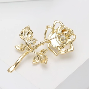 Elegant gold-tone rose brooch with white shell petals and detailed leaf design