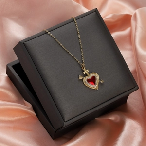 Detail of red heart necklace with zircon arrow pendant in premium black gift box on silk