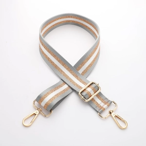 Macro shot of striped canvas bag strap with golden metal swivel hooks on white backdrop