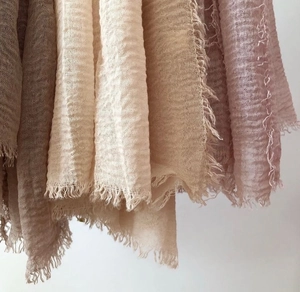 Detail of crinkle cotton linen scarf featuring natural fringe edges and textured fabric