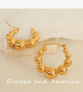 Macro detail of large gold bubble hoop earrings featuring a minimalist geometric design