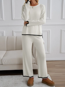 Close-up of white knit set featuring black contrast trim on sleeves and pant hems