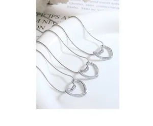 Detail of silver heart pendant necklaces on a round snake chain over a white ceramic plate