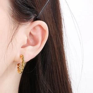 Gros plan détaillé d'une boucle d'oreille créole torsadée en C dorée sur un mannequin