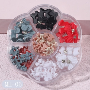 Detailed view of floral-shaped storage box with assorted 3D nail art bows and rhinestones