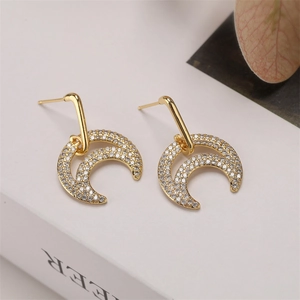 Detail shot of gold-plated crescent earrings with micro-pave crystals on white surface