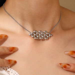Gros plan d'un collier argenté avec pendentif tissé géométrique sur une chaîne serpent