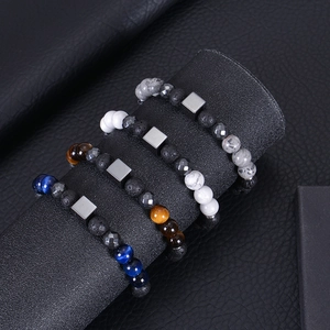 Detailed shot of four natural lava rock and tiger eye beaded bracelets for men on black leather