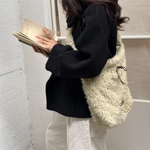 Detail of cream sherpa bucket bag with drawstring and brown leather trim on a model