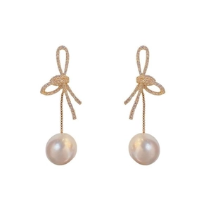 Golden knot bow earrings with pavé crystals and elegant round pearl pendants on white background