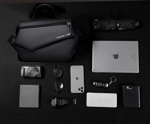 Flat lay of black crossbody bag showing spacious interior with iPad and daily gadgets