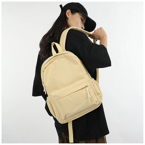 Detailed view of beige corduroy backpack with front pocket being worn by a model
